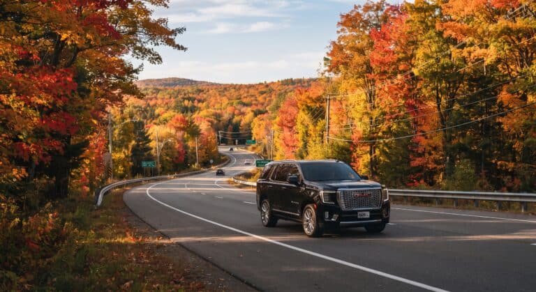 Black GMC Yukon SUV on an autumn Ontario highway for long-distance car service