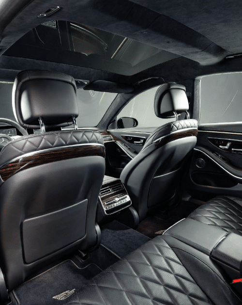 Interior of a premium Mercedes S-Class showing leather seating and executive mobile office amenities.