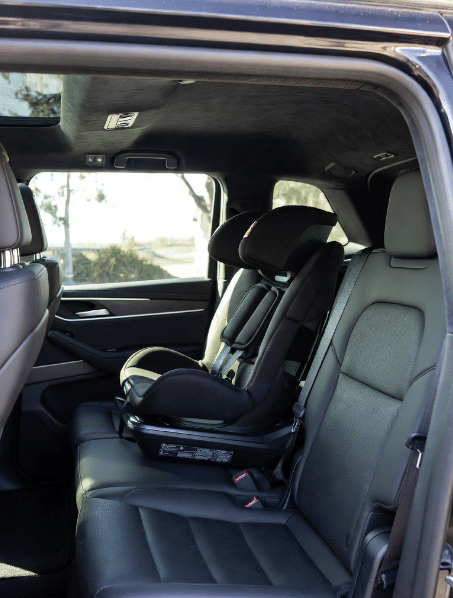 A professional forward-facing toddler car seat securely installed in the black leather interior of a luxury VVIP Toronto Limo SUV.