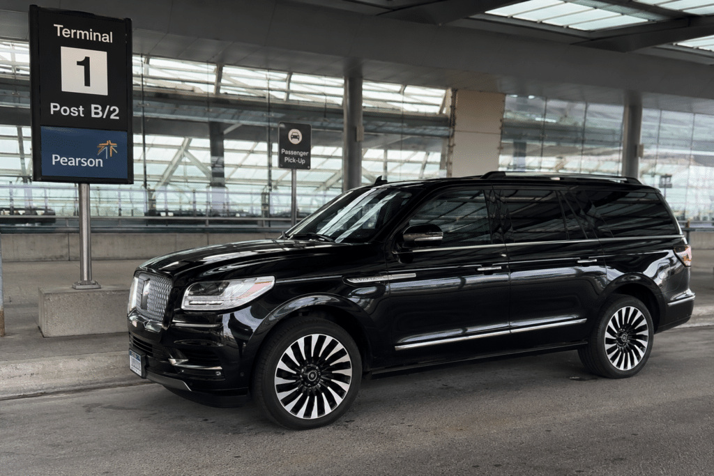 Black luxury Lincoln Navigator SUV parked at Toronto Pearson Airport Terminal 1, Post B2, for passenger pickup service.