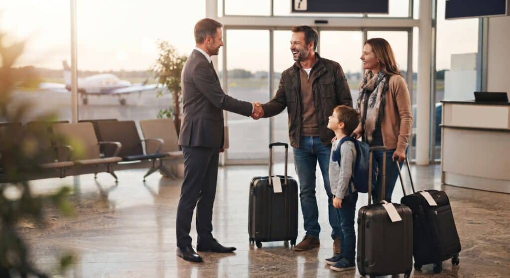 Chauffeur shaking hands with a family with suitcases in the arrivals hall for a Waterloo airport pickup